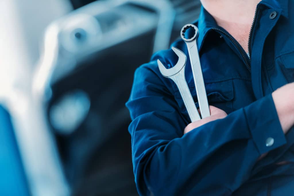 closeup of mechanic holding combination wrenches