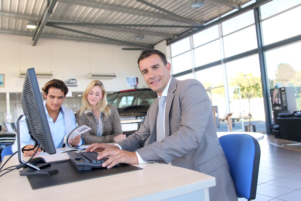 Car seller and a couple of buyers signing contract